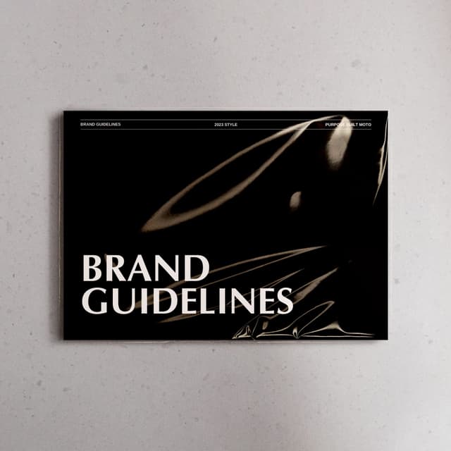 A brand guidelines booklet for Purpose Built Moto hangs on a grey wall, its cover showing abstract motorcycle imagery.
