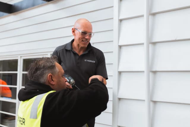 A St Ferrer director and a tradesperson laughing while working on the weatherboard cladding
