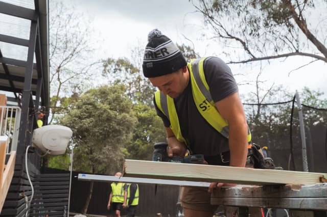 Trades and volunteers building the new deck at the back of the house on build day