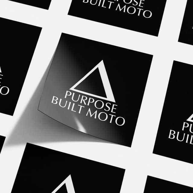 A tiled sheet of black stickers reading Purpose Built Moto with a triangle logo.
