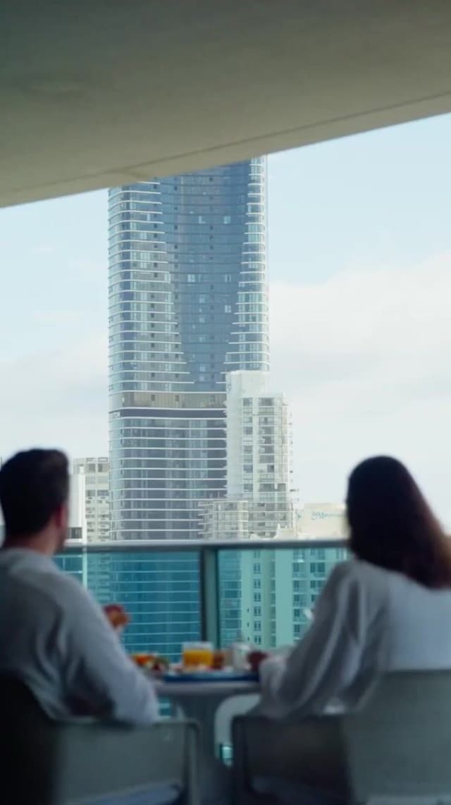 A couple has breakfast on a balcony overlooking city skyscrapers at a Hilton Surfers Paradise hotel.