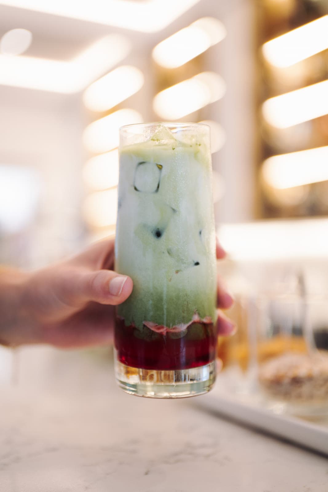 A layered matcha drink held up at the Hilton Surfers Paradise bar